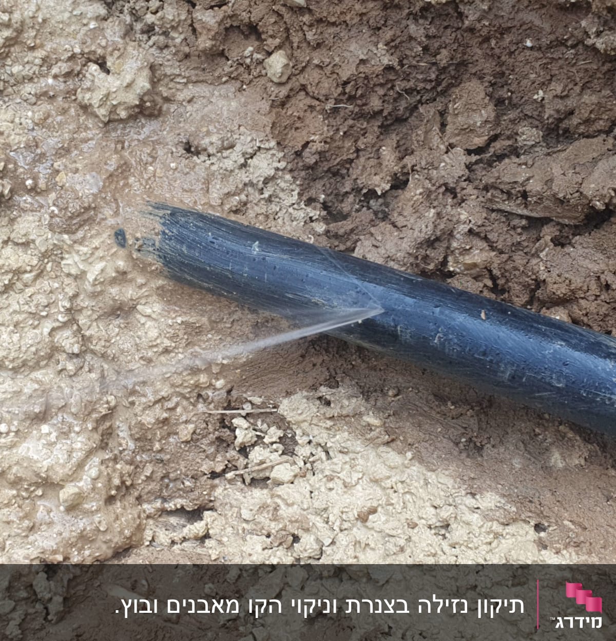 צינור שחור דולף מים באדמה רטובה